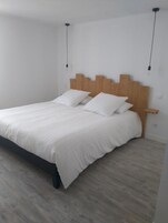 Un dormitorio con cabecera de madera, dos almohadas blancas y suelo de madera.