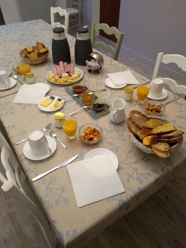 A breakfast table set with various dishes, including toast, fruit, and beverages. - La maison de pescate (Souprousse)