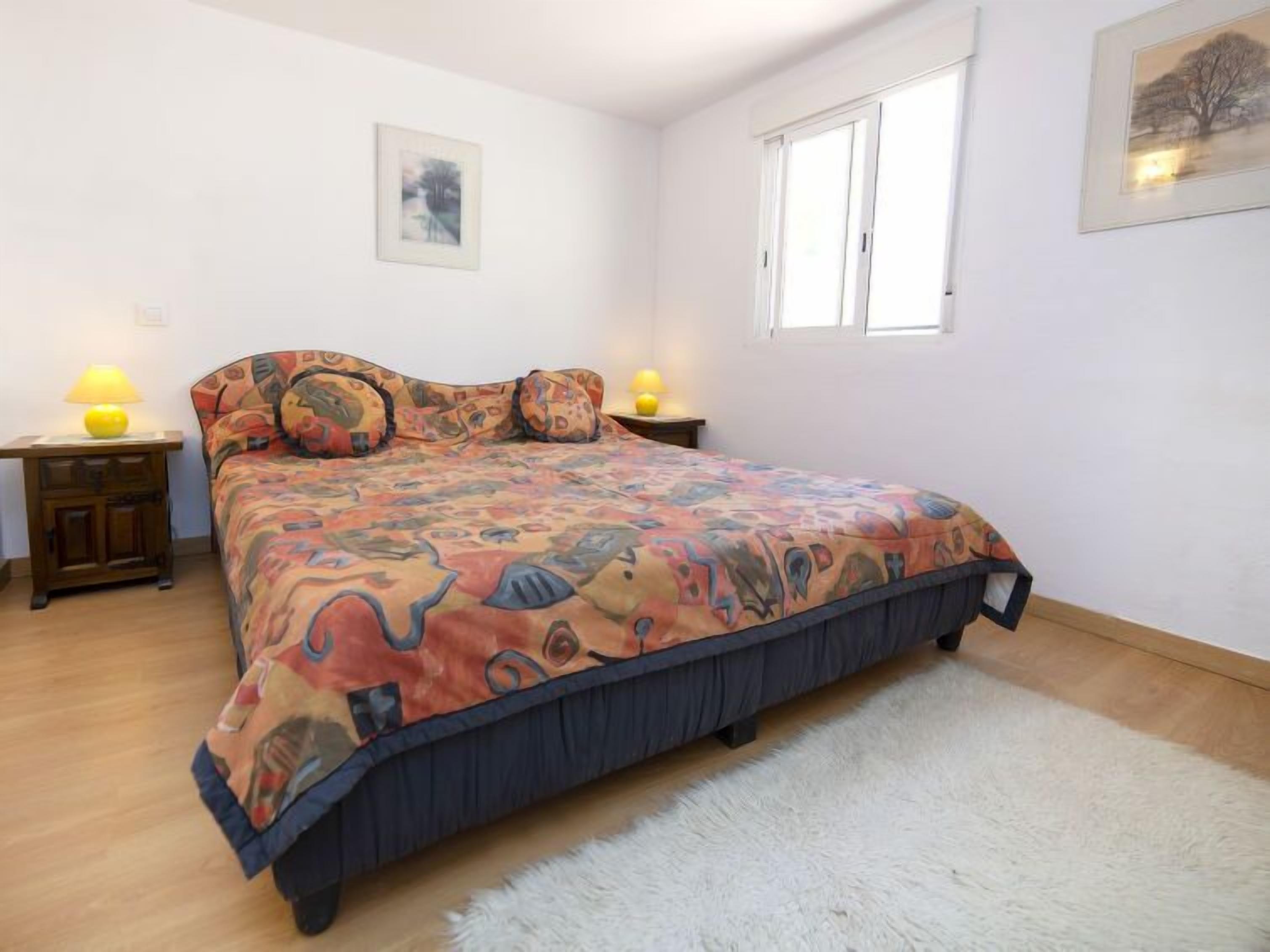 Ein Schlafzimmer mit einem Bett, zwei Nachttischen, einem Fenster und einem Teppich.