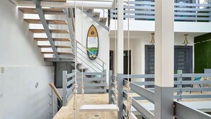 A modern interior with a staircase, a surfboard decoration, and a view of the outside. - Colonial Beach House (Santo Domingo)