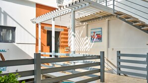 A modern outdoor seating area with a metal fence and a staircase leading to an upper level. - Colonial Beach House (Santo Domingo)