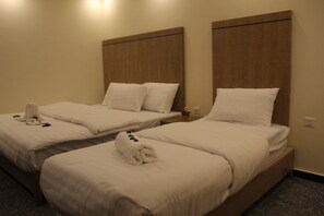 Two single beds with wooden headboards, white bedding, and a rolled towel on the bed. - Holiday aqaba hotel (Aqaba)