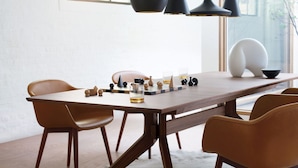 Un comedor moderno con una mesa de madera, sillas marrones e iluminación colgante.