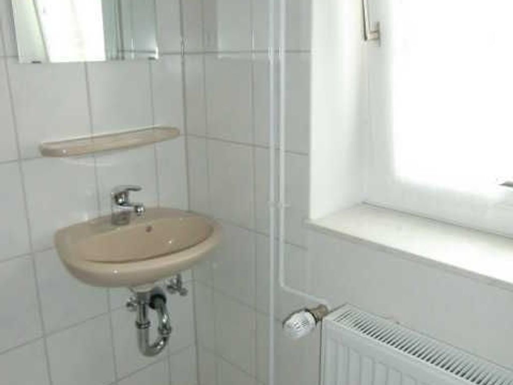 Een badkamer met een wastafel, spiegel en raam.