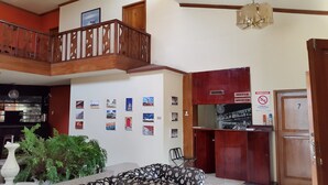 A hotel lobby with a reception desk, a staircase, and a wall decorated with various photographs. - Golden Mar Hostal (Manta)