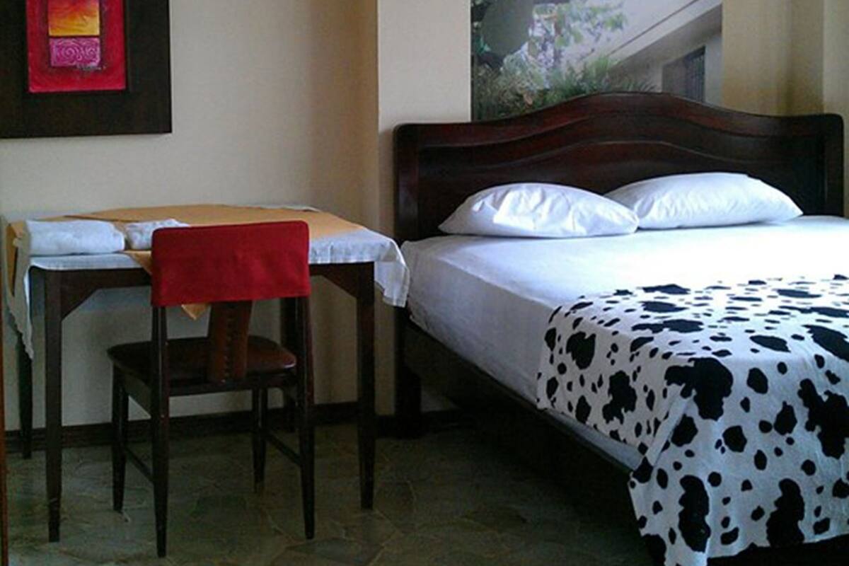 Ein Schlafzimmer mit Bett, Schreibtisch, Stuhl, Deckenventilator und Klimaanlage.