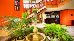 A lobby with a staircase, a bar area, and various potted plants. - Golden Mar Hostal (Manta)