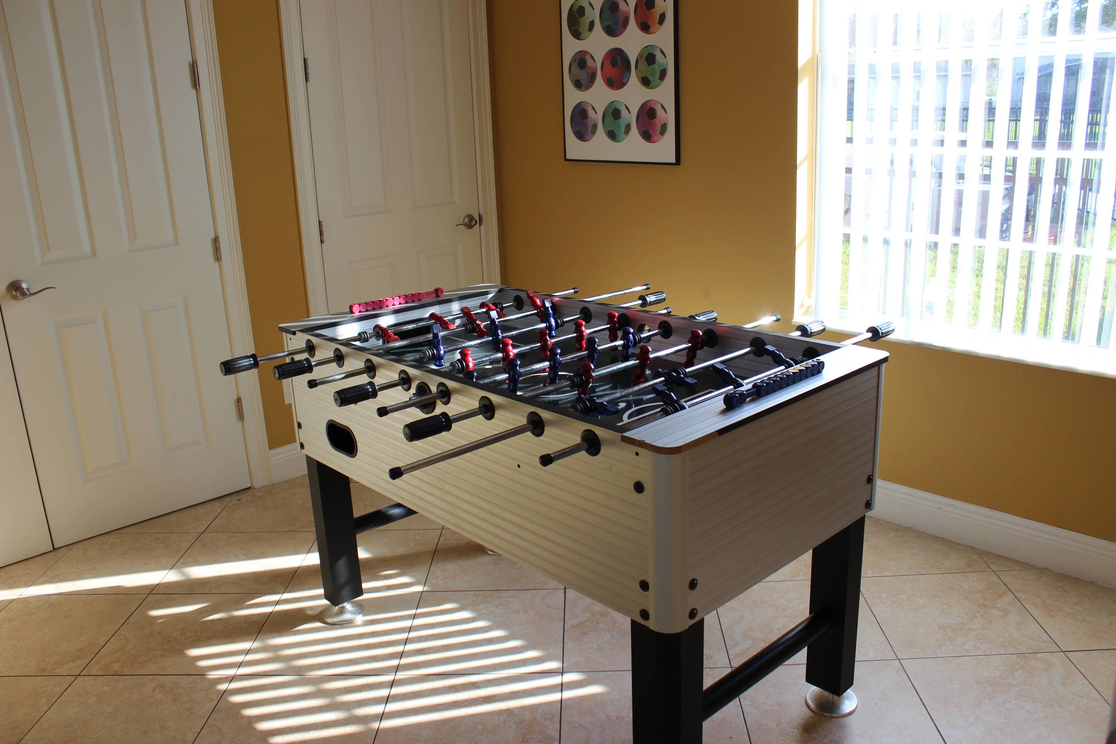 A foosball table in a room with a door and a window.
