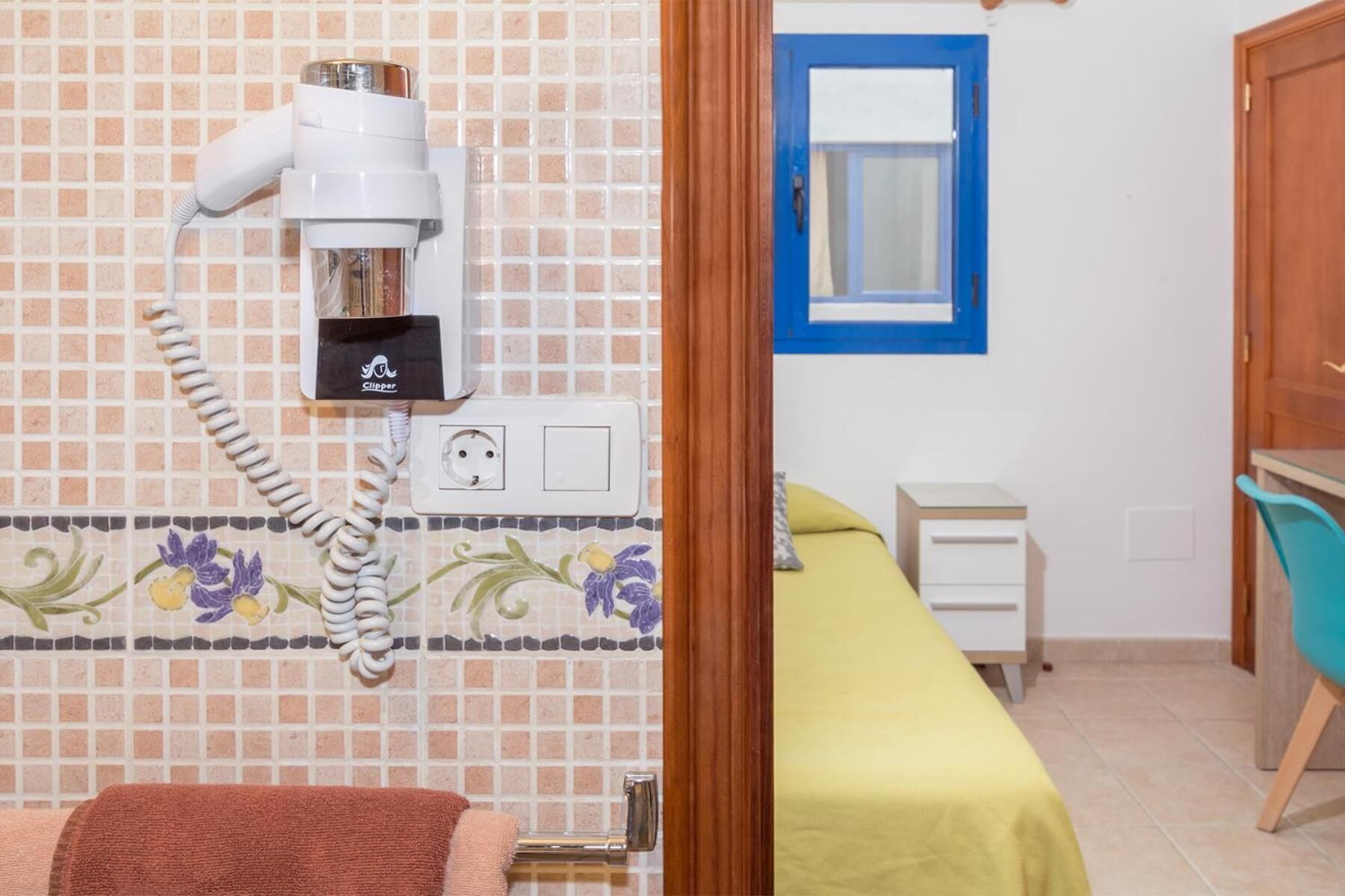 Ein Hotelzimmer mit Bad, einem Bett, einem Schreibtisch und einem Stuhl.
