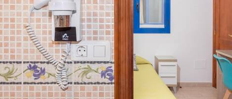 A hotel room with a bathroom, a bed, a desk, and a chair.