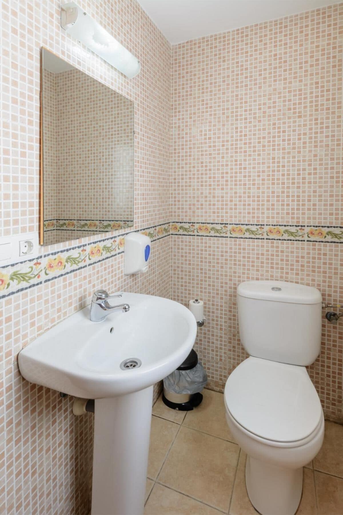 Une salle de bain avec un lavabo blanc, des toilettes et un miroir.