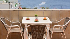 A balcony with two wicker chairs and a small table, overlooking the ocean. - Pensión MAGEC (Tías)