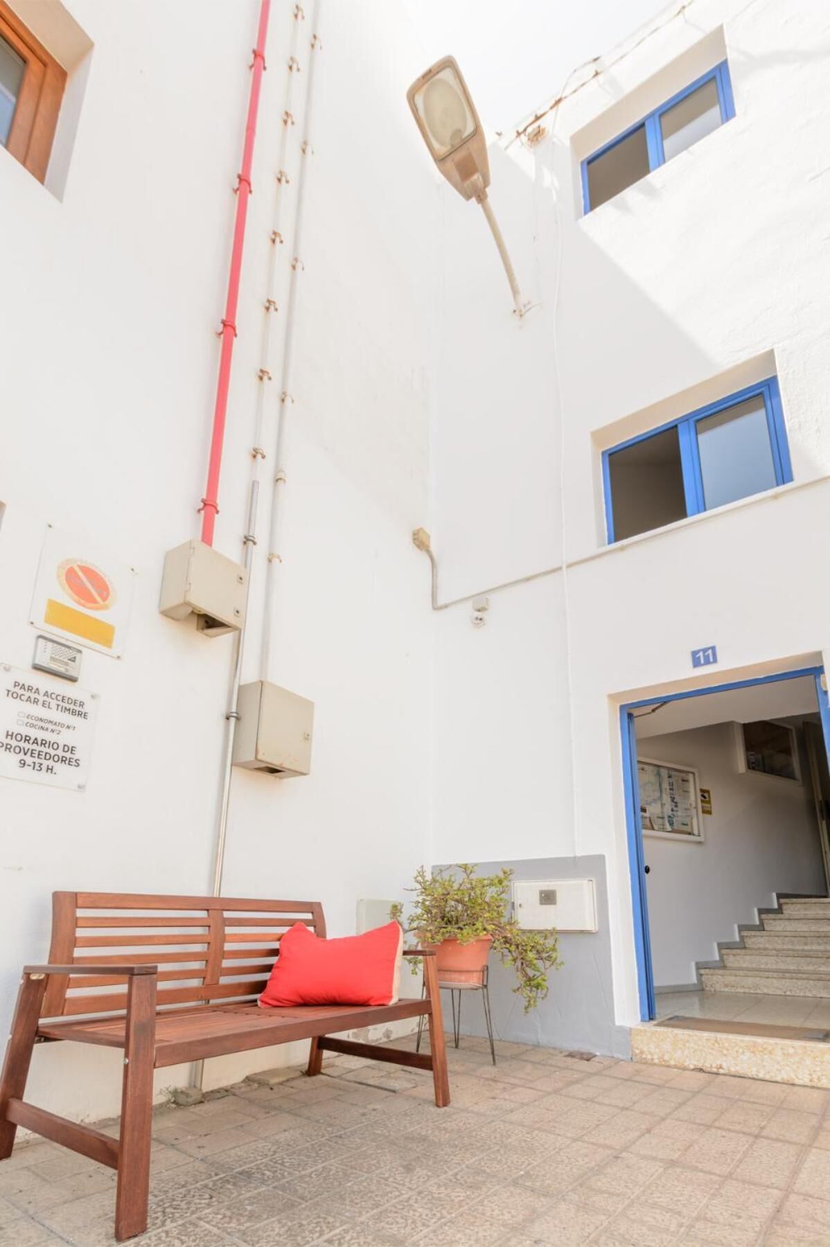 Un bâtiment avec un banc, un pot de fleurs et un escalier menant à une entrée.