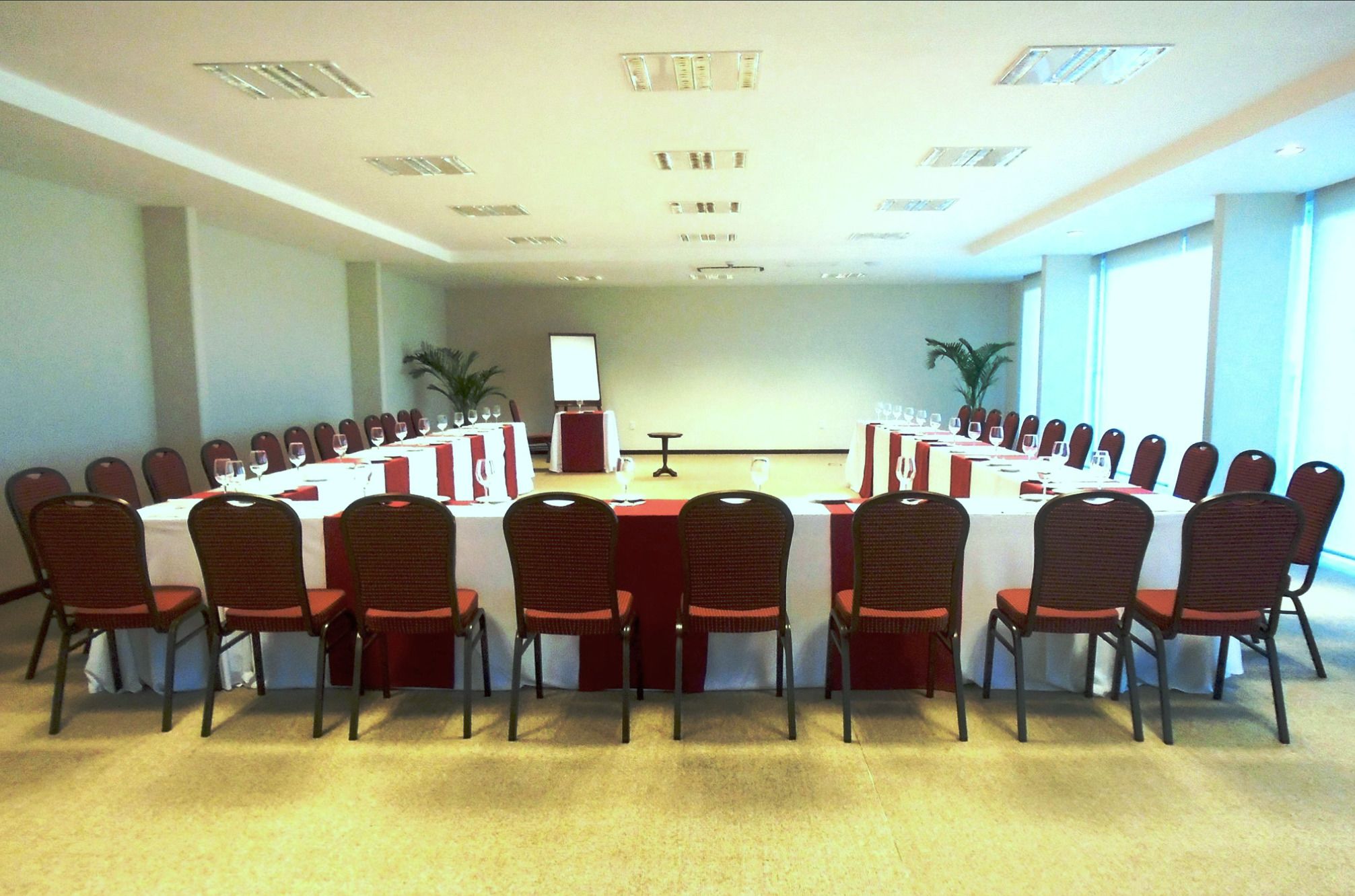 Uma sala de conferência com uma mesa comprida, cadeiras e um pódio.