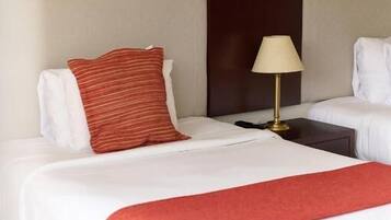 Una habitación de hotel con una cama grande, una mesita de noche, una lámpara y una manta roja.