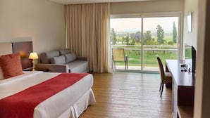 Een hotelkamer met een bed, een bureau, een bank en een balkon met uitzicht op het platteland.