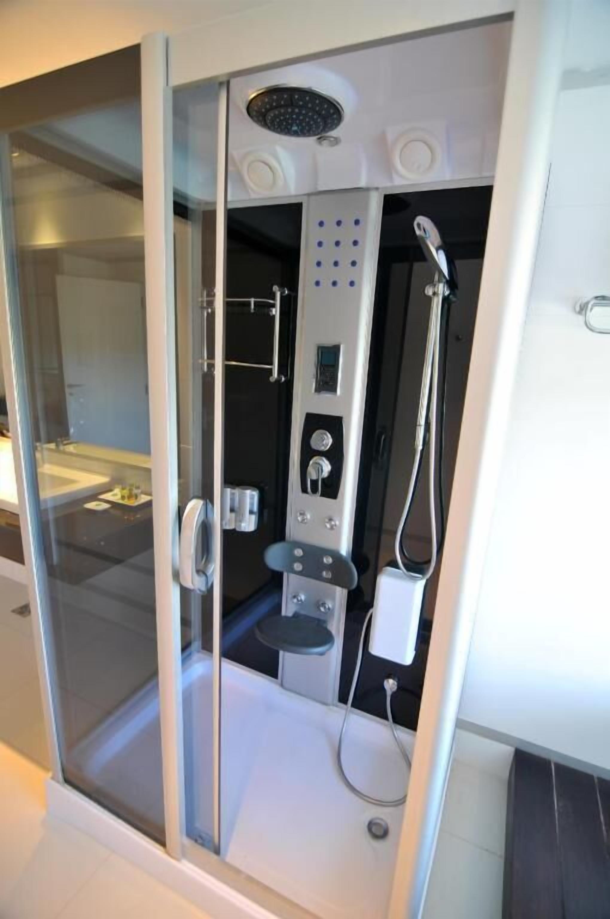 A modern bathroom with a glass enclosure, a showerhead, control panel, and a handheld shower attachment.