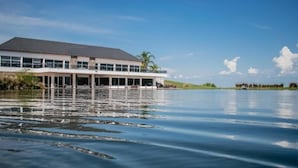Een modern gebouw met een plat dak, grote ramen en uitzicht op het water.
