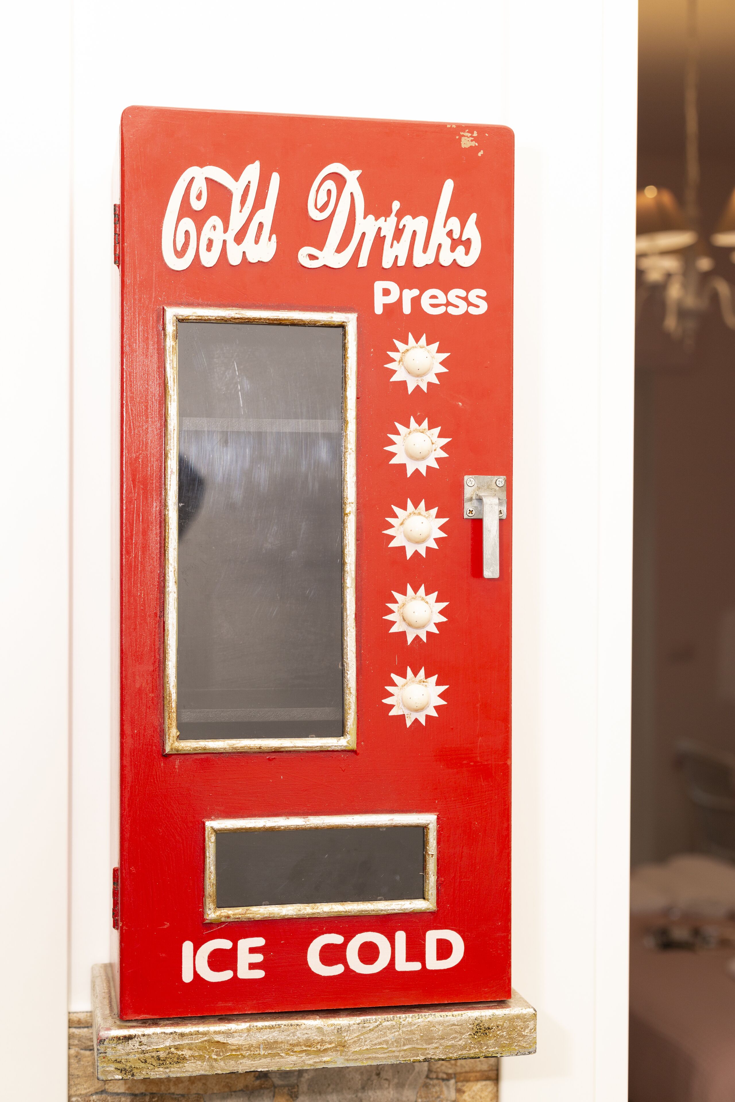 A red vending machine with the text "Cold Drinks Press" and "Ice Cold" on it.