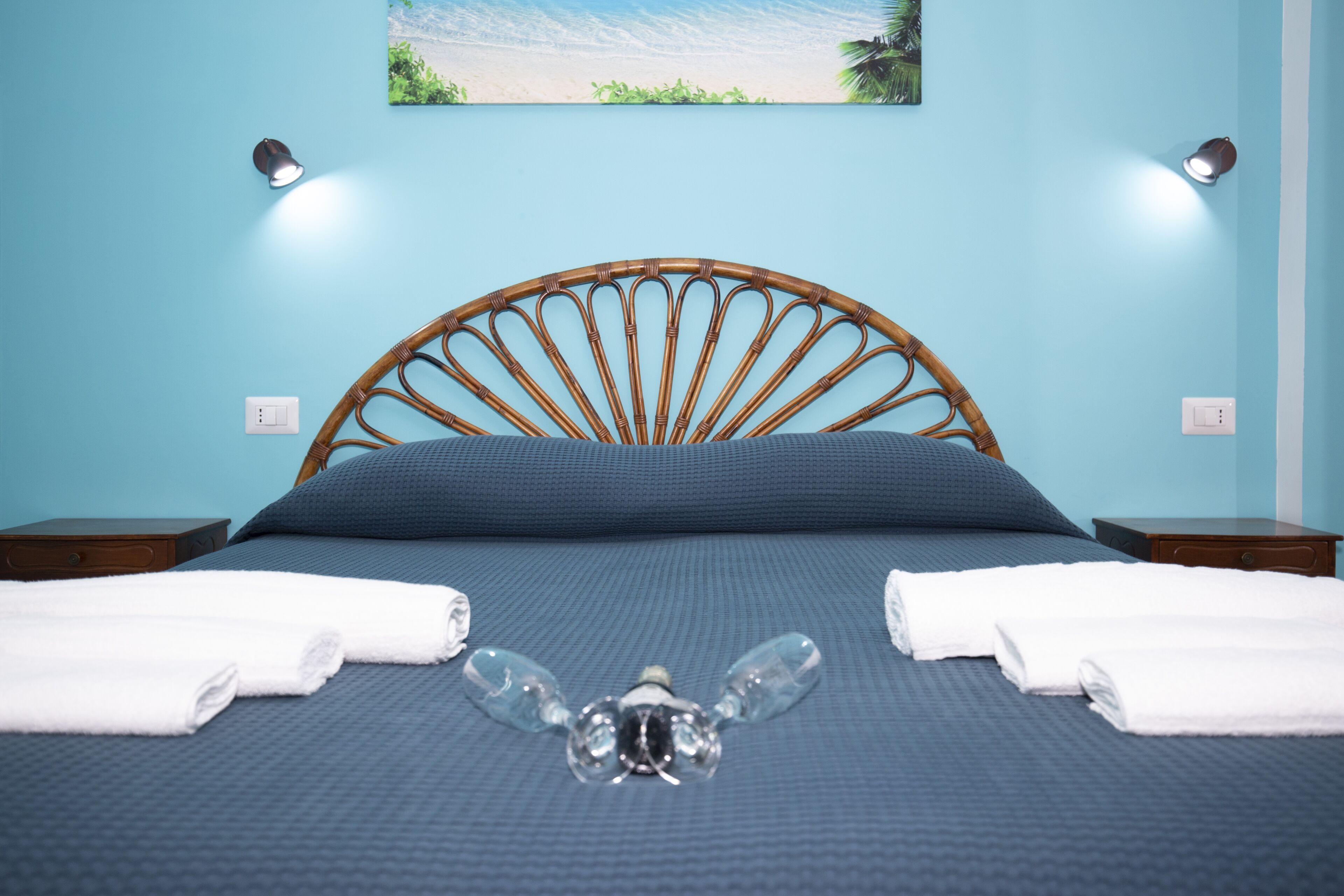 Un lit bien fait, avec une couvre-lit bleue, deux serviettes blanches et un objet décoratif placé au centre.