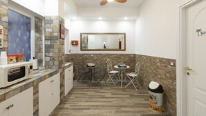 A compact kitchen with a microwave, two dining tables, and chairs. - ViOletta (Rome)