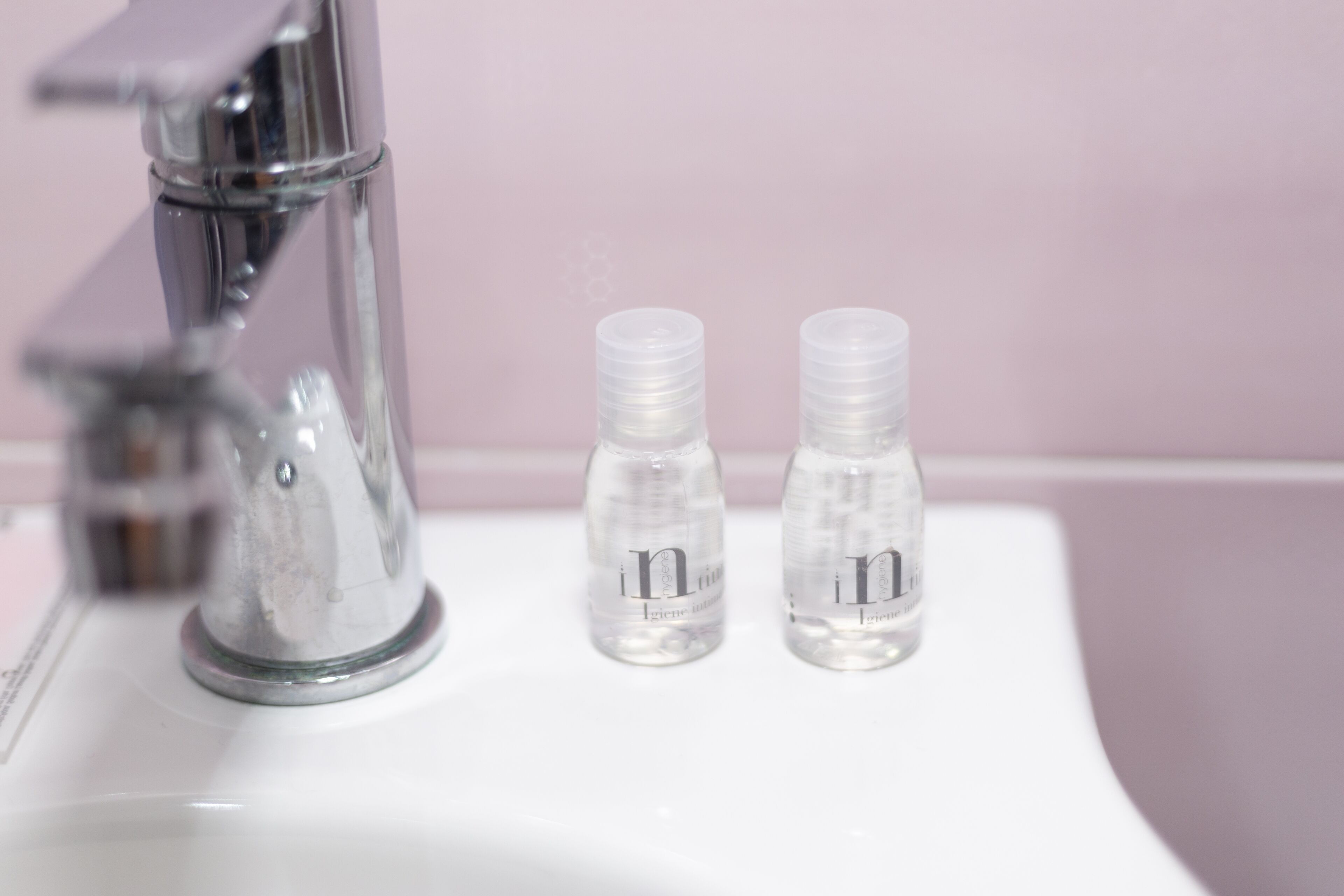Un lavabo de salle de bain avec un robinet chromé et deux bouteilles transparentes portant un logo.