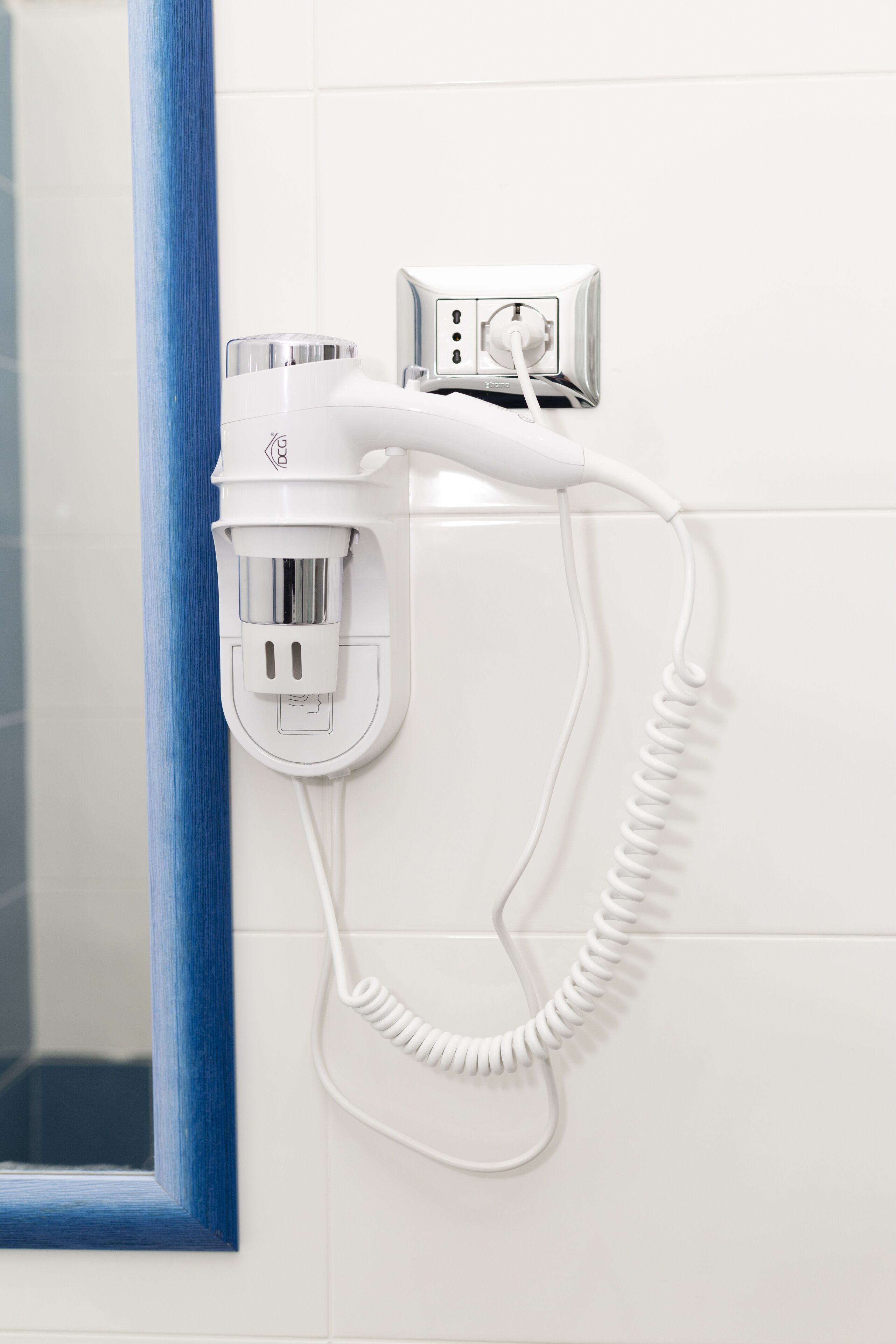 A hair dryer and a power strip mounted on a white tiled wall.