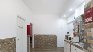 A modern kitchen with a stone backsplash, white cabinets, and a microwave on the counter. - ViOletta (Rome)