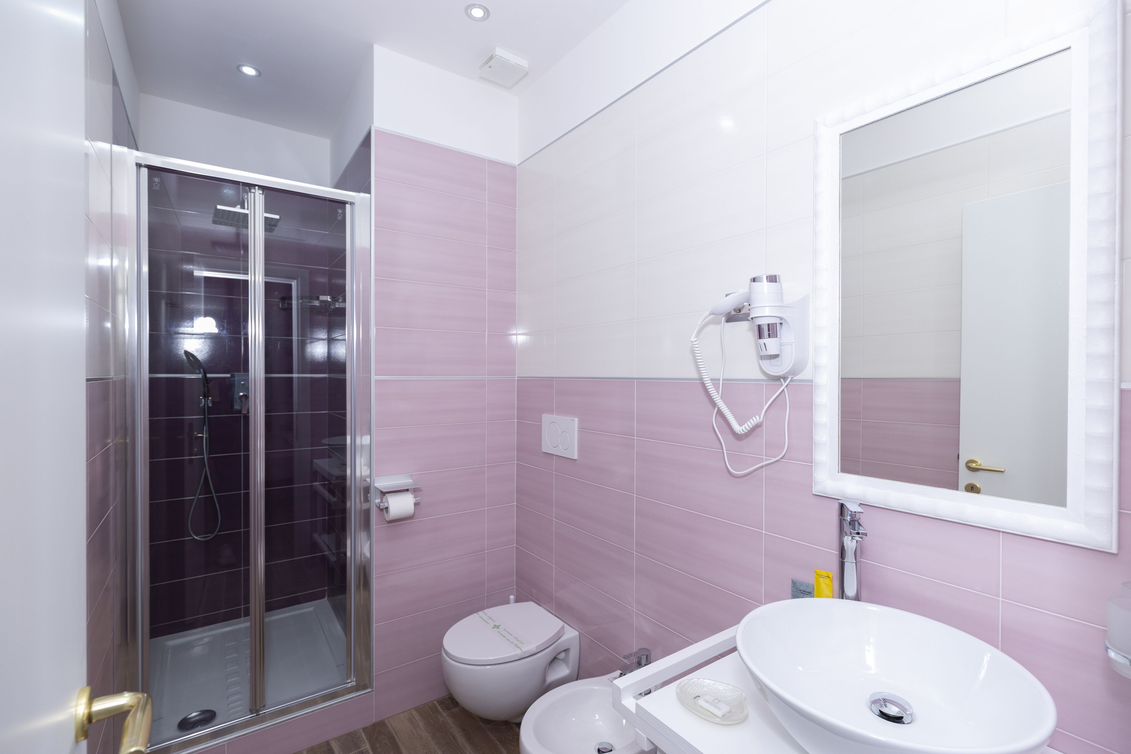 A bathroom with a glass-enclosed shower, a toilet, and a sink with a mirror above it.