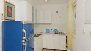 A compact kitchen with white cabinets, a blue refrigerator, and a small sink. - Apartments Branislav (Rogoznica)
