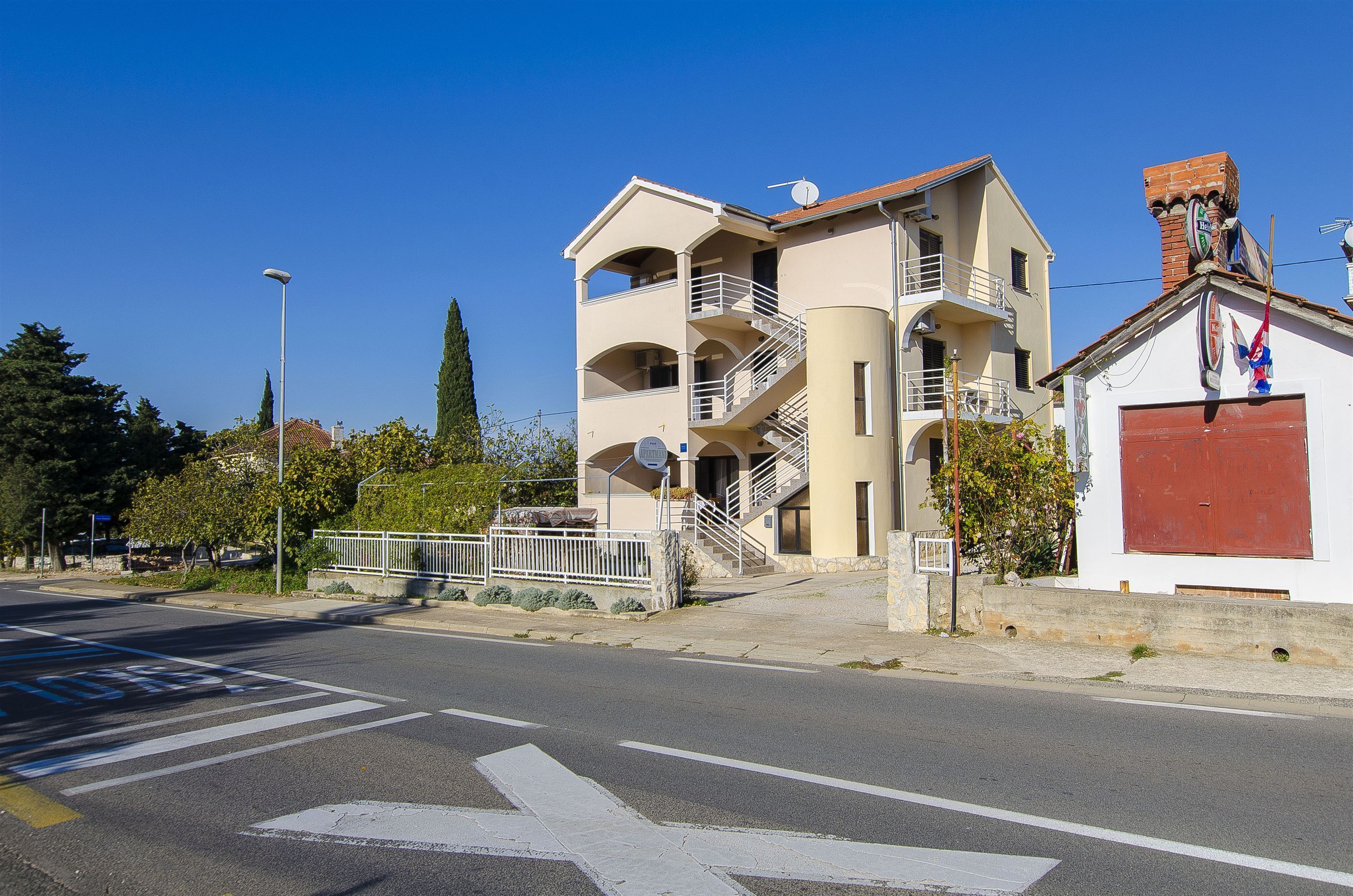 A multi-story building with balconies, a staircase, and a garage.