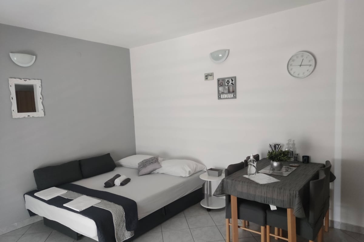 Ein modernes Schlafzimmer mit Bett, Nachttisch und einer kleinen Essecke mit Tisch und Stühlen.