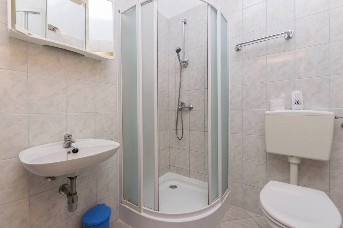 A bathroom with a glass-enclosed shower, a sink, and a toilet.