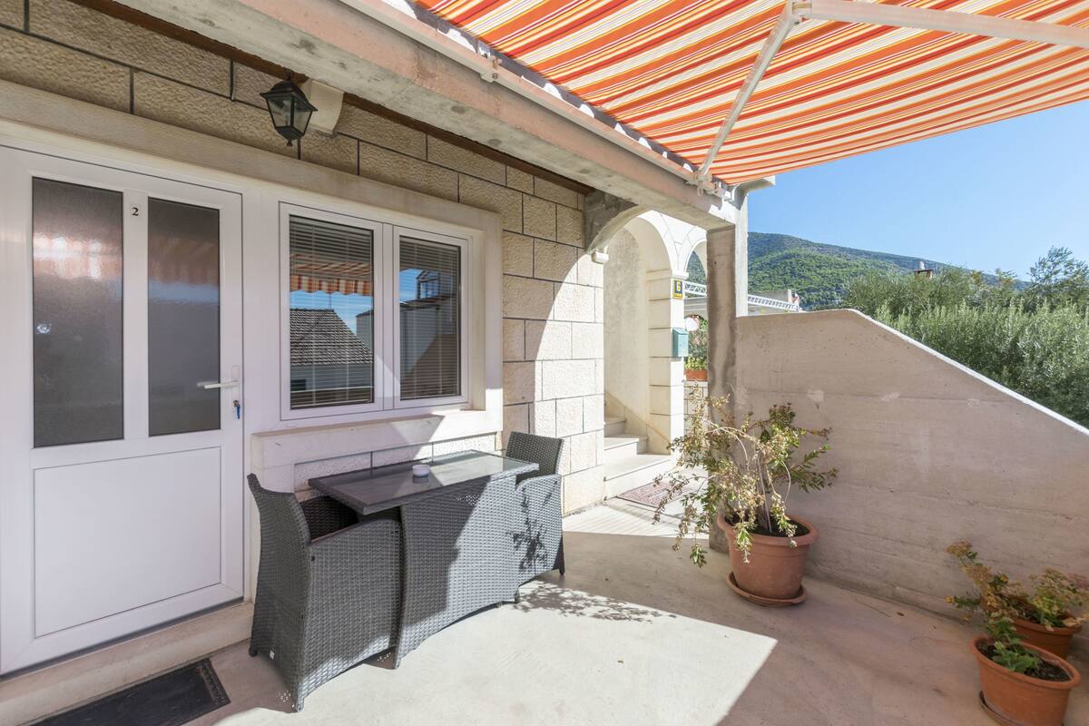 A balcony with a table and chairs, potted plants, and a view of a mountain.