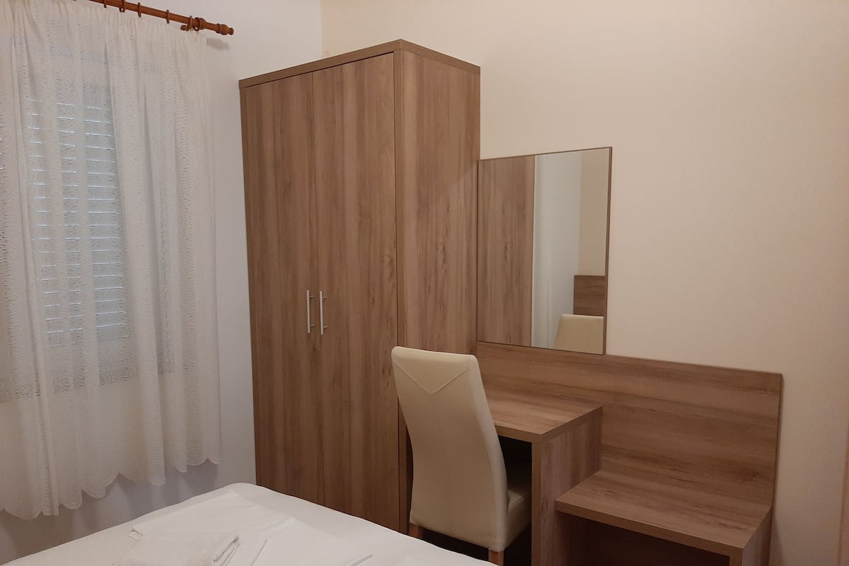 A bedroom with a wooden wardrobe, a desk, and a chair.