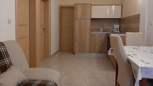 Cocina pequeña con armarios de madera, una mesa de comedor y un sofá.