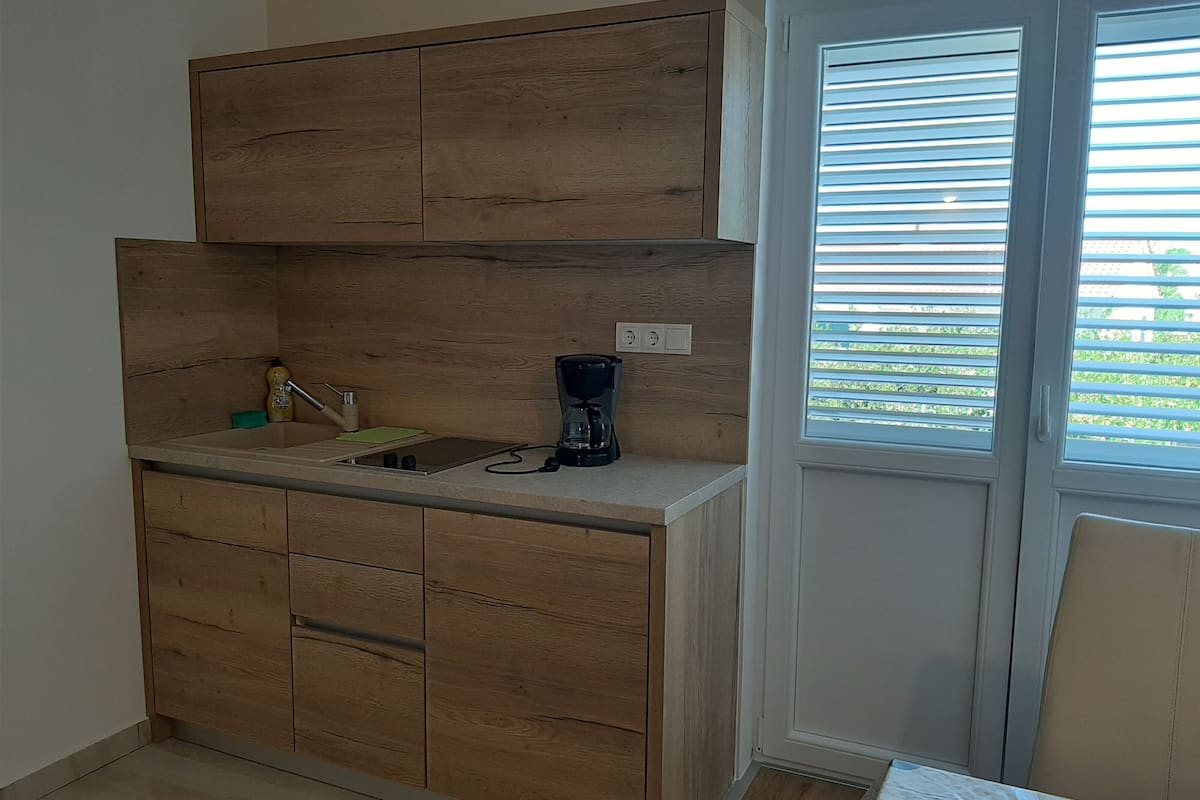 A compact kitchen with wooden cabinets, a sink, and a coffee maker.