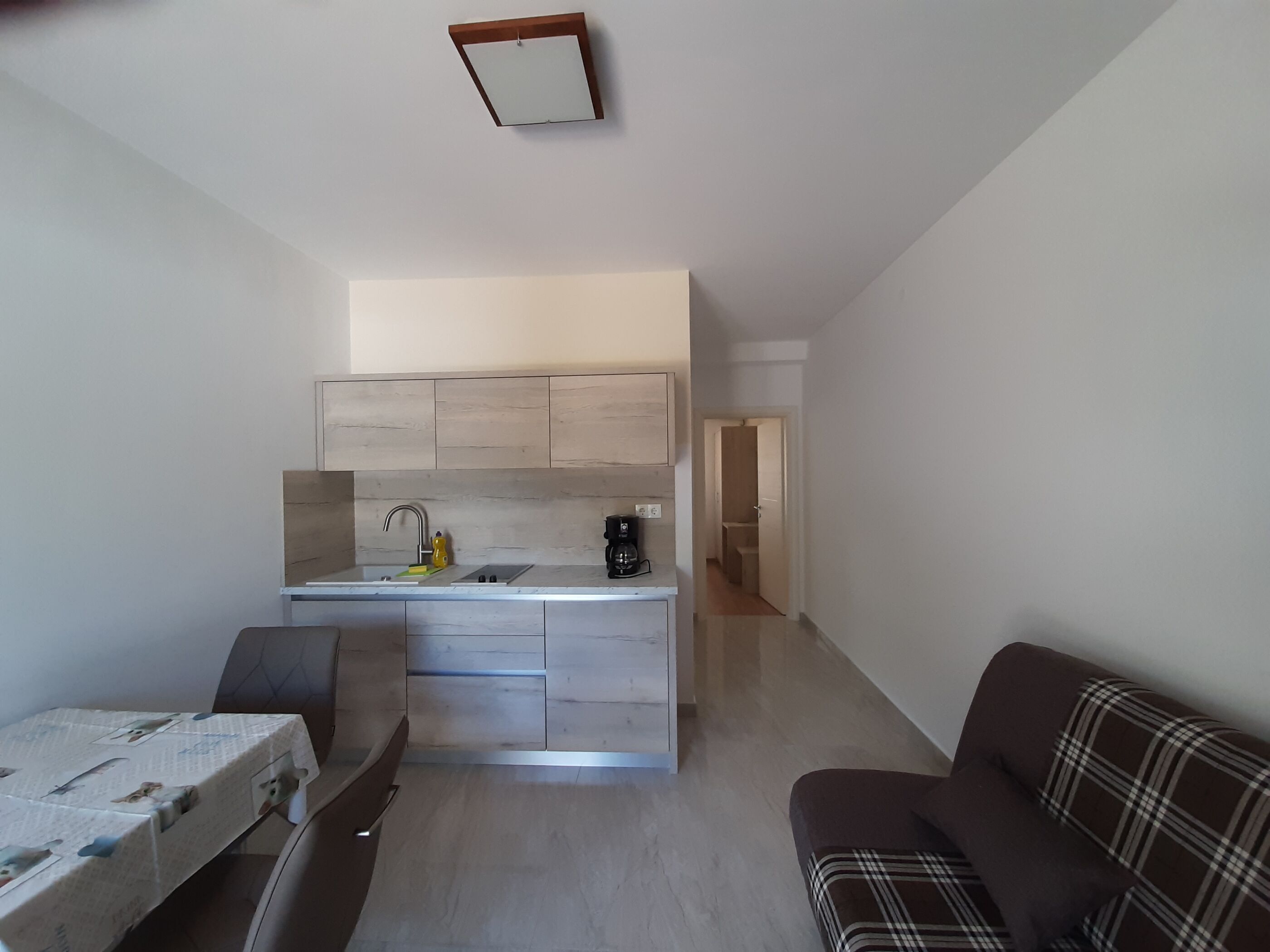 A modern kitchen with a central island, a dining area with a table, and a living area with a couch.
