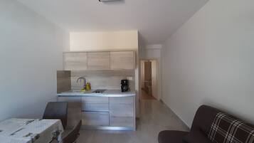 A modern kitchen with a central island, a dining area with a table, and a living area with a couch.
