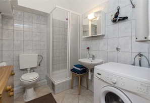 A bathroom with a toilet, shower, sink, and washing machine. - Apartment Brankica Vodice (Vodice)