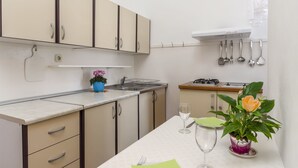 Una cocina con armarios color beige, un fregadero, una estufa y una planta en maceta.