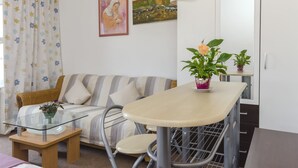 Una sala de estar con un sofá, una mesa de vidrio y dos plantas en macetas.