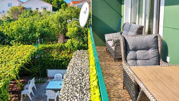 Un balcon avec un canapé en osier, une table à manger avec des chaises et une antenne parabolique.