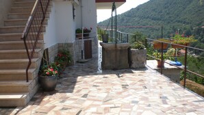 A tiled outdoor area with a staircase leading to a balcony, potted plants, and a view of a mountainous landscape. - Apartment Marino (Moscenicka Draga)