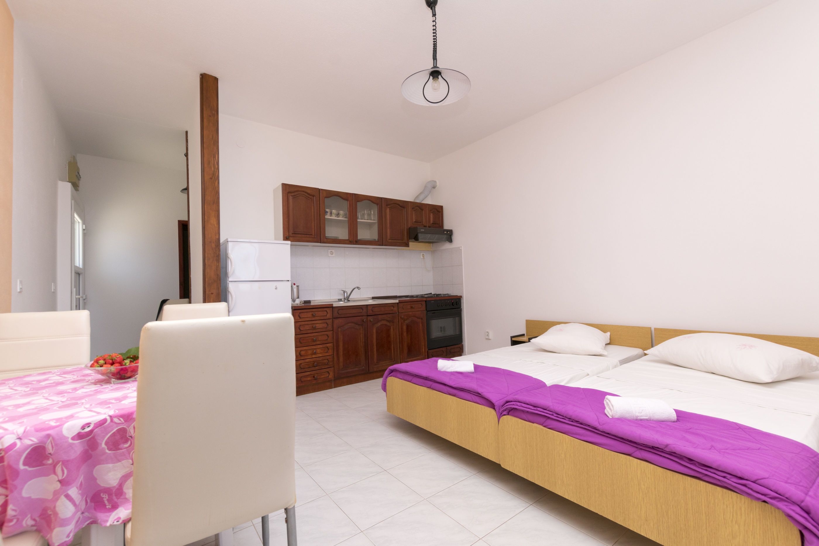 A bedroom with a bed, a small table, and a kitchenette.
