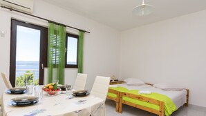 A room with a bed, a table set for dining, and a view of the sea. - Apartments A Cappella Music (Lokva Rogoznica)
