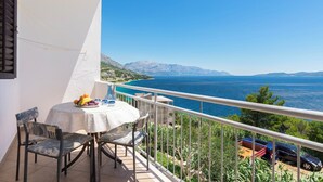 A balcony with a table and chairs, overlooking a scenic view of the sea and mountains. - Apartments A Cappella Music (Lokva Rogoznica)