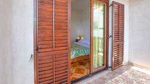 A bedroom with a bed, a nightstand, and a window with curtains. - Apartments Marica (Sukosan)