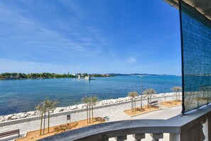 Une vue sur la côte, avec un ciel dégagé, une promenade dallée et un banc.