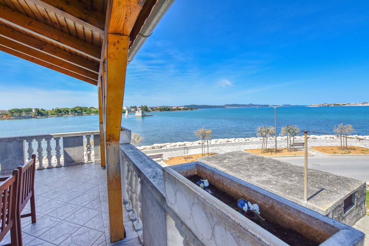 Ein Balkon mit Meerblick, mit Fliesenboden und einer Holz-Pergola.